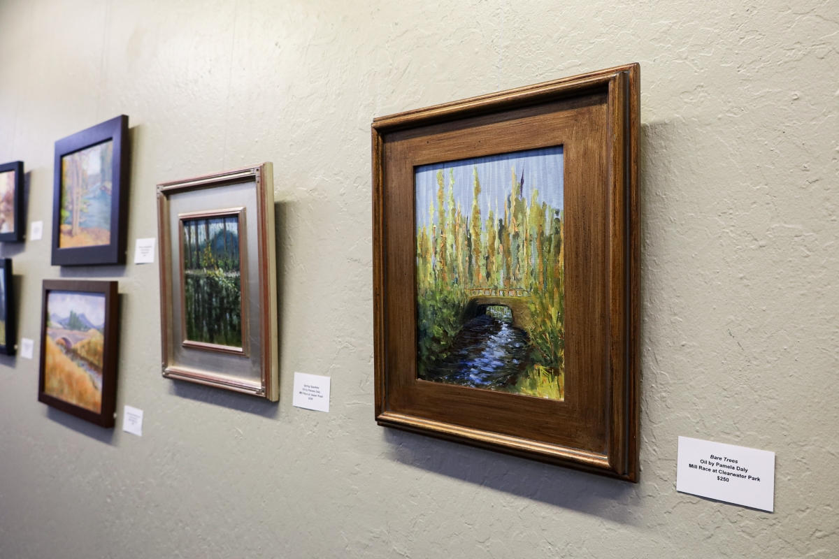 A collection of assorted frames and local art hanging on a beige wall.