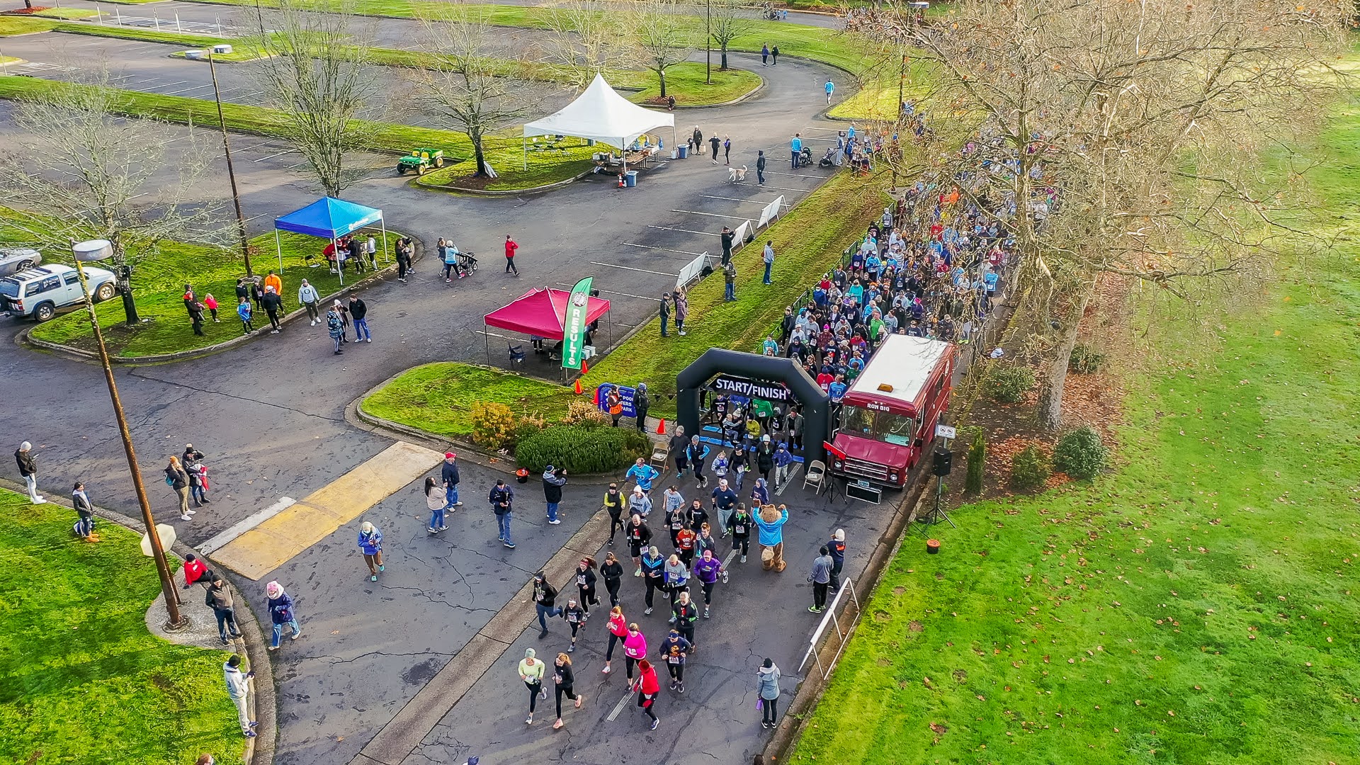 Birds-eye view of a 5k start line with people starting to walk and run on the road.