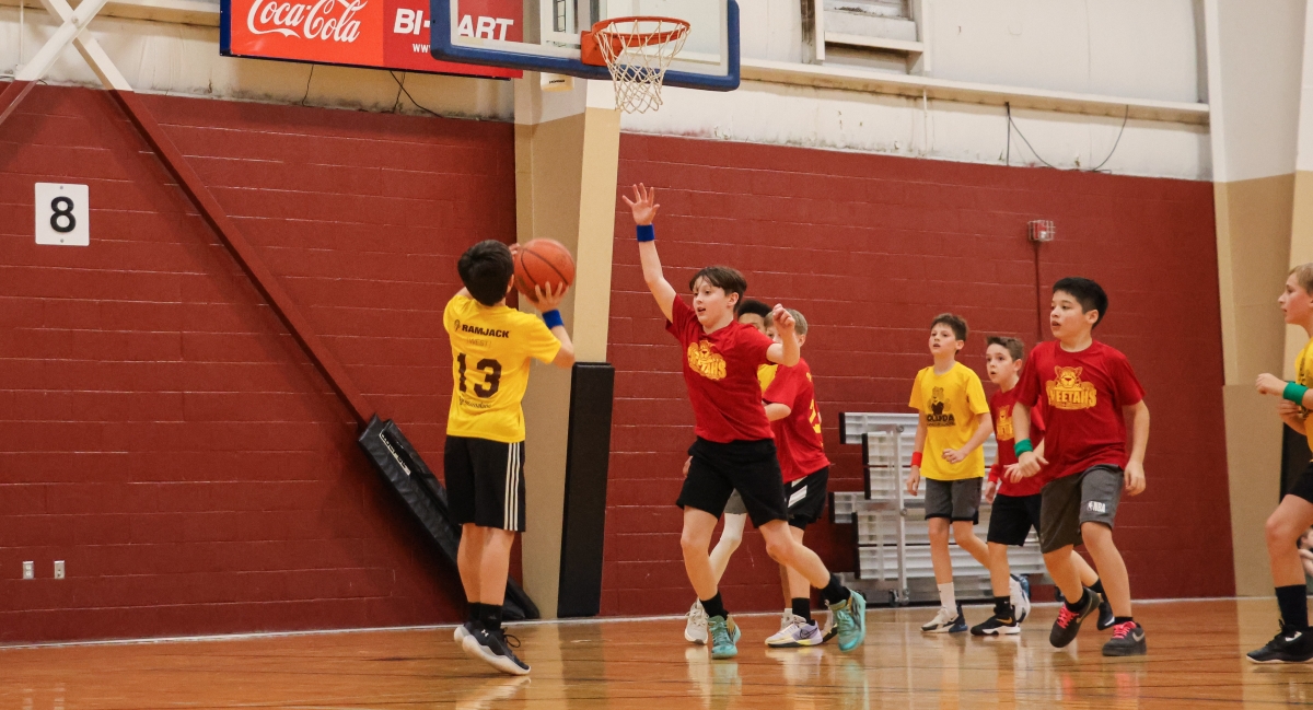 Two basketball teams in red and yellow jerseys passing the ball between players.