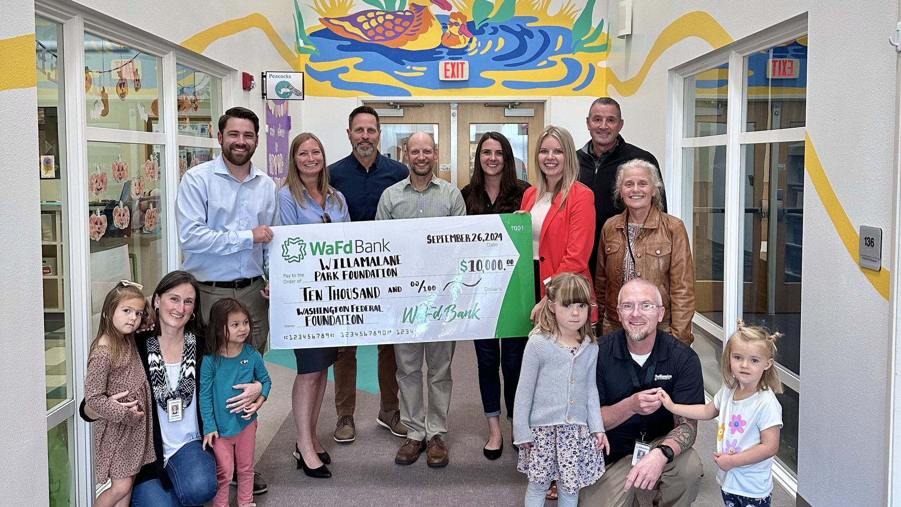 Willamalane staff, foundation members, preschoolers, and donors stand inside new preschool in front of $10,000 giant check