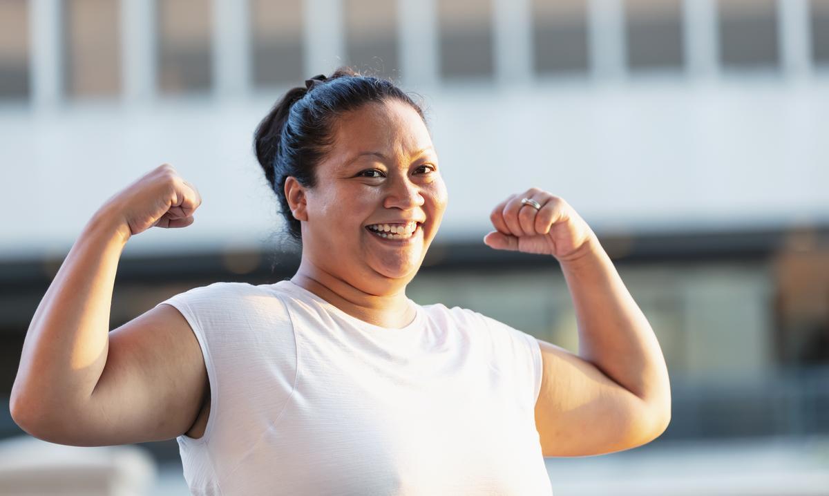 An adult poses confidently with their arms flexed.