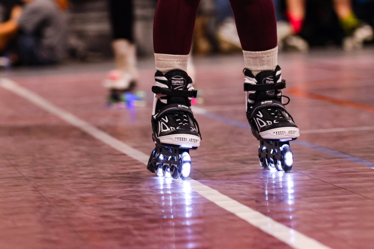 A pair of black and white skates glides along the floor.