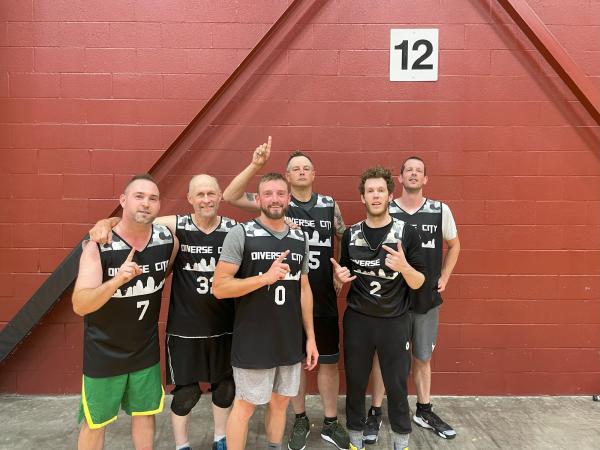 six men in matching black jerseys pose for a photo holding up "number one"