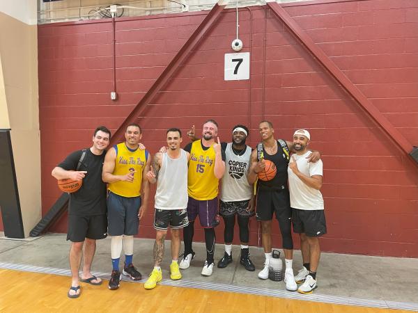 Seven men pose in the gym holding "number one" up on their hands