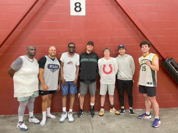 Seven men pose in the gym