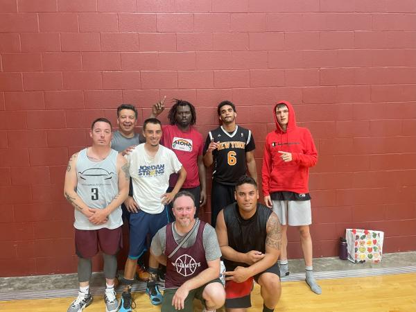 eight men pose in the gym, most with straight faces