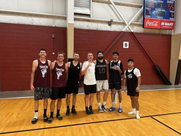 seven men pose in a line in the gym