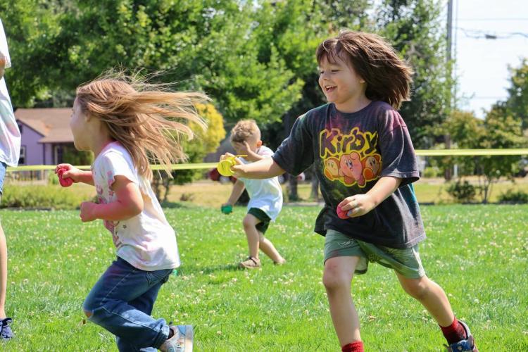 Two young children running in a grassy area.