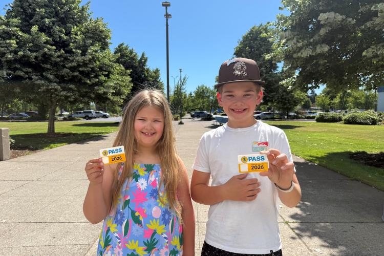 Two kids stand holding their 1pass cards
