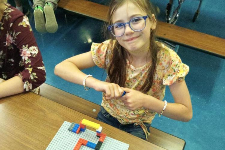 A child smiles with colored blocks in their hands.