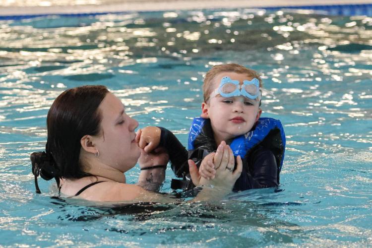 Teacher helps student swim in the water