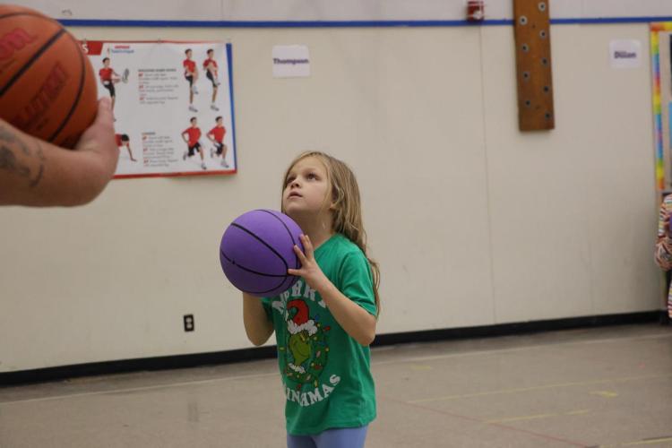 A child stands with a purple basketball.