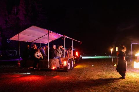 A trailer glows in the night, with fire dancers alongside.
