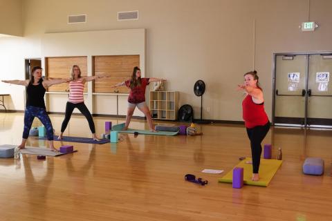 Four adults strike a yoga pose in a dimly lit room.