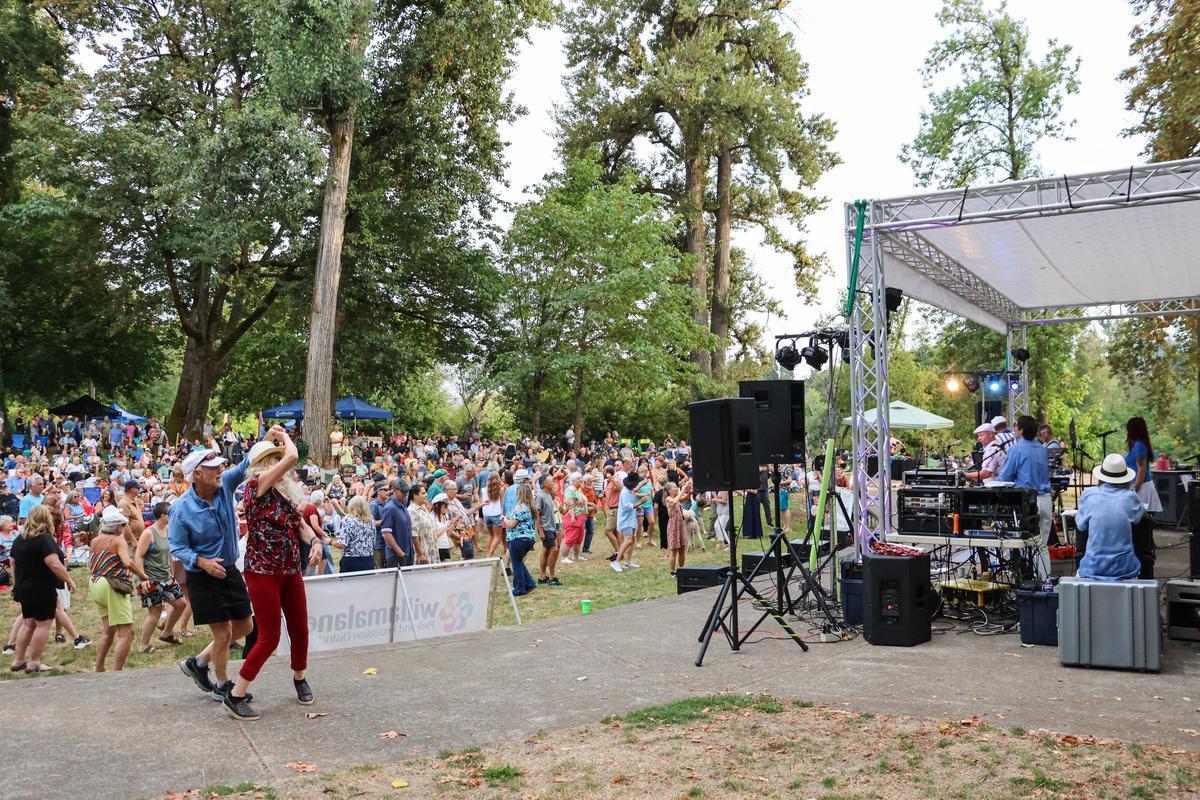 A crowd stands in front of an outdoor stage.