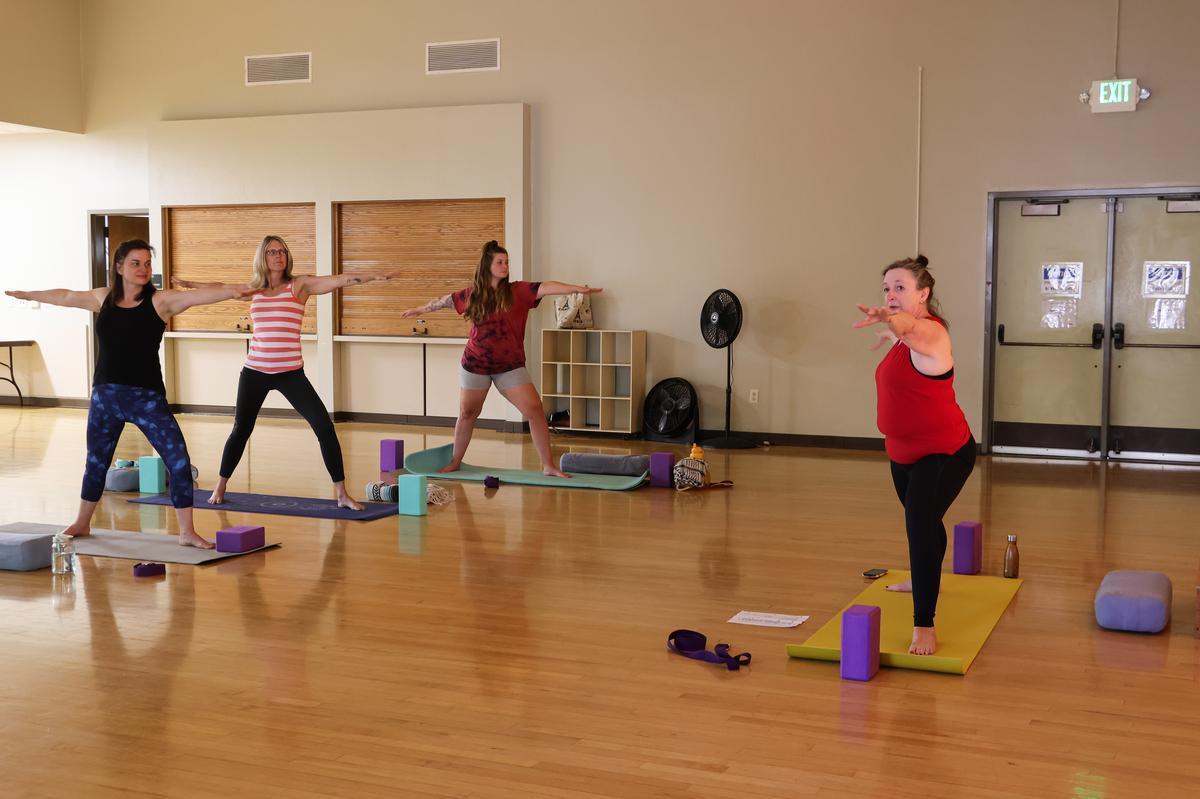 Four adults strike a yoga pose in a dimly lit room.