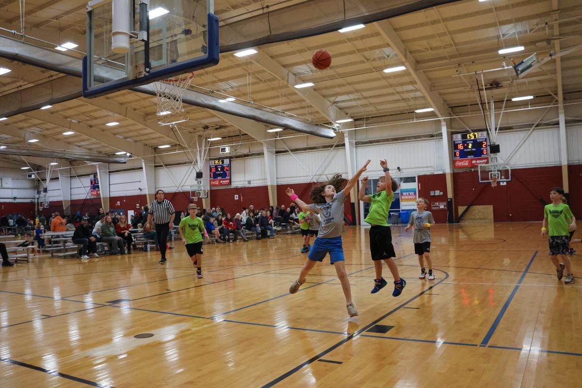 A team of players wearing green and gray toss a ball into the air.