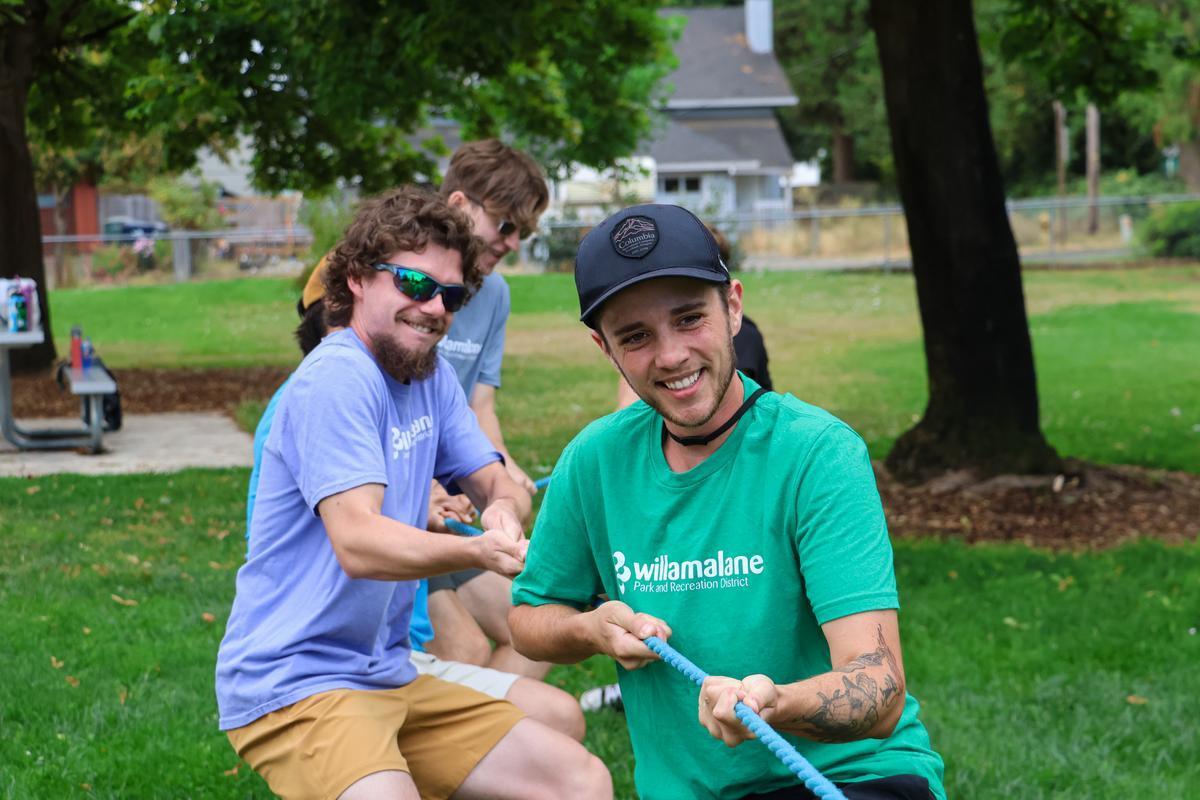 A group of adults pulls a rope against a team of kids.