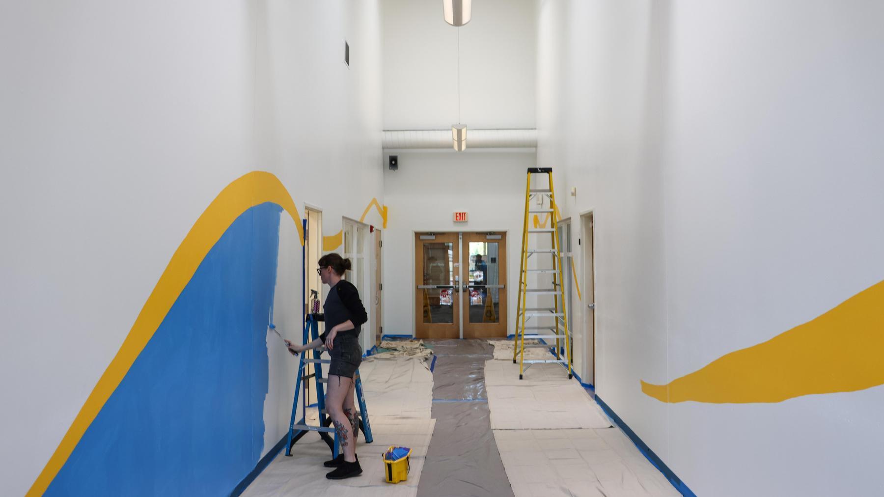 An artist paints an indoor mural
