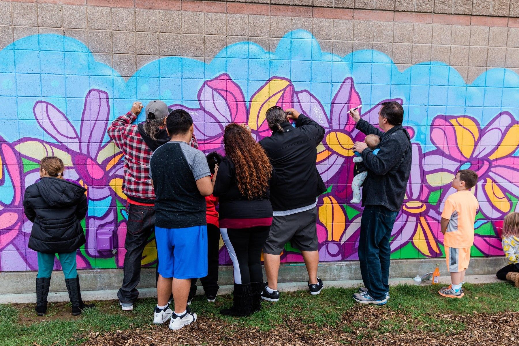 Community members sign a large mural