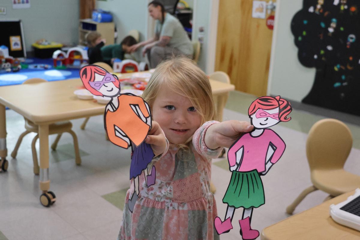 A child holds up two art projects.