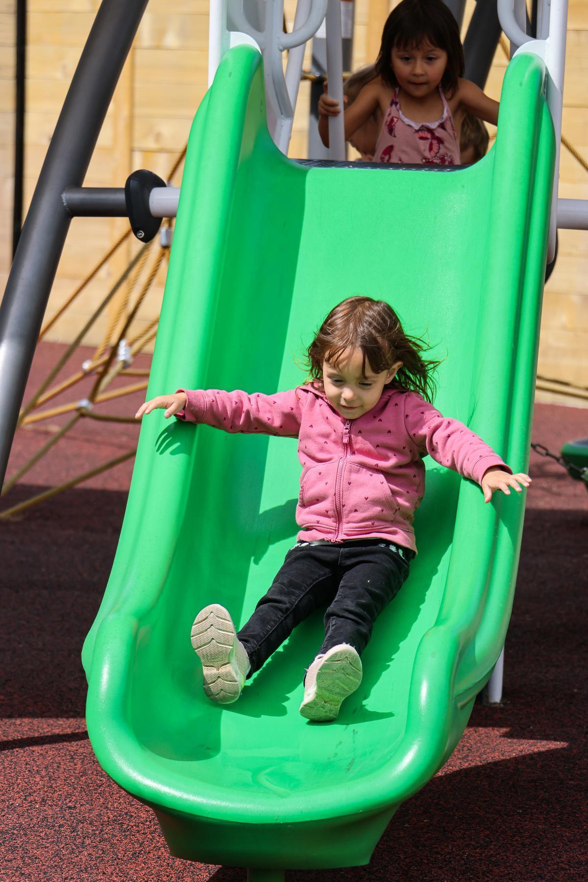 A child slides down a small green slide.