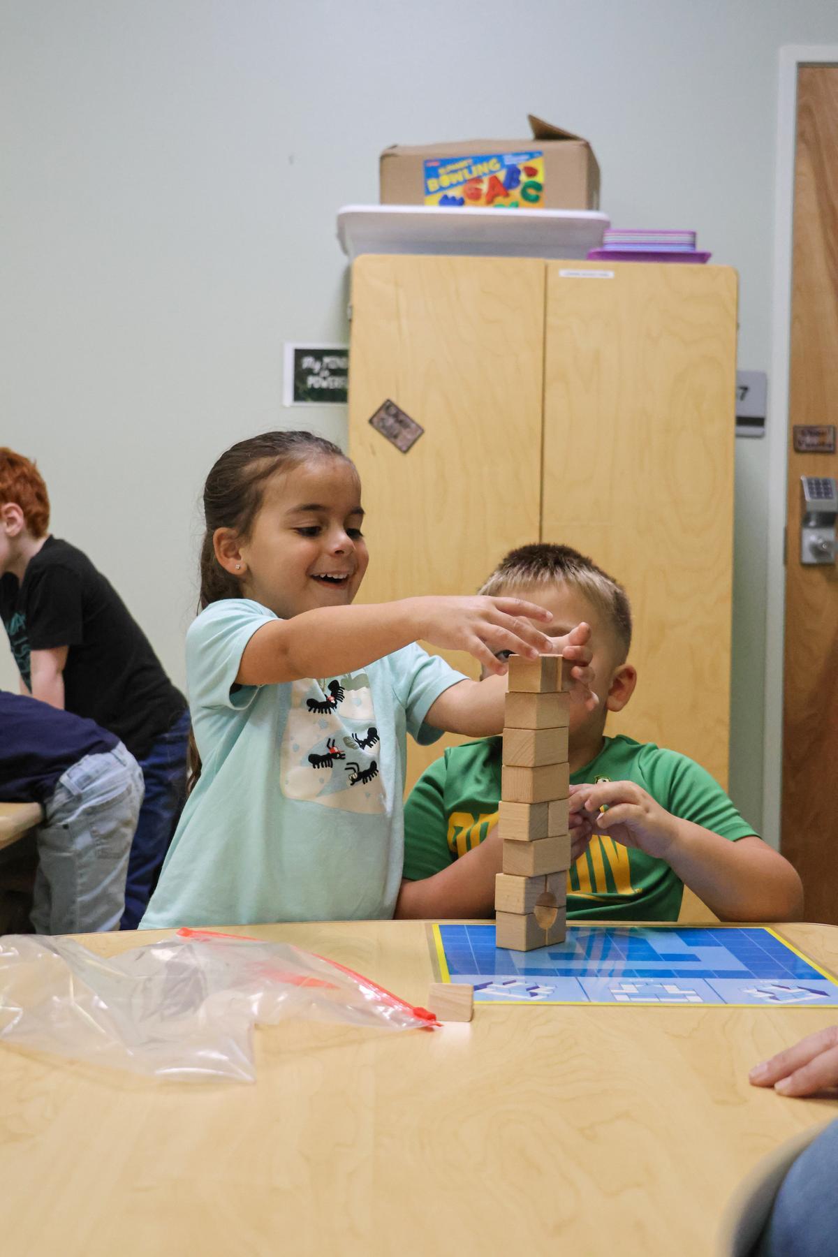 Two children stack blocks together.