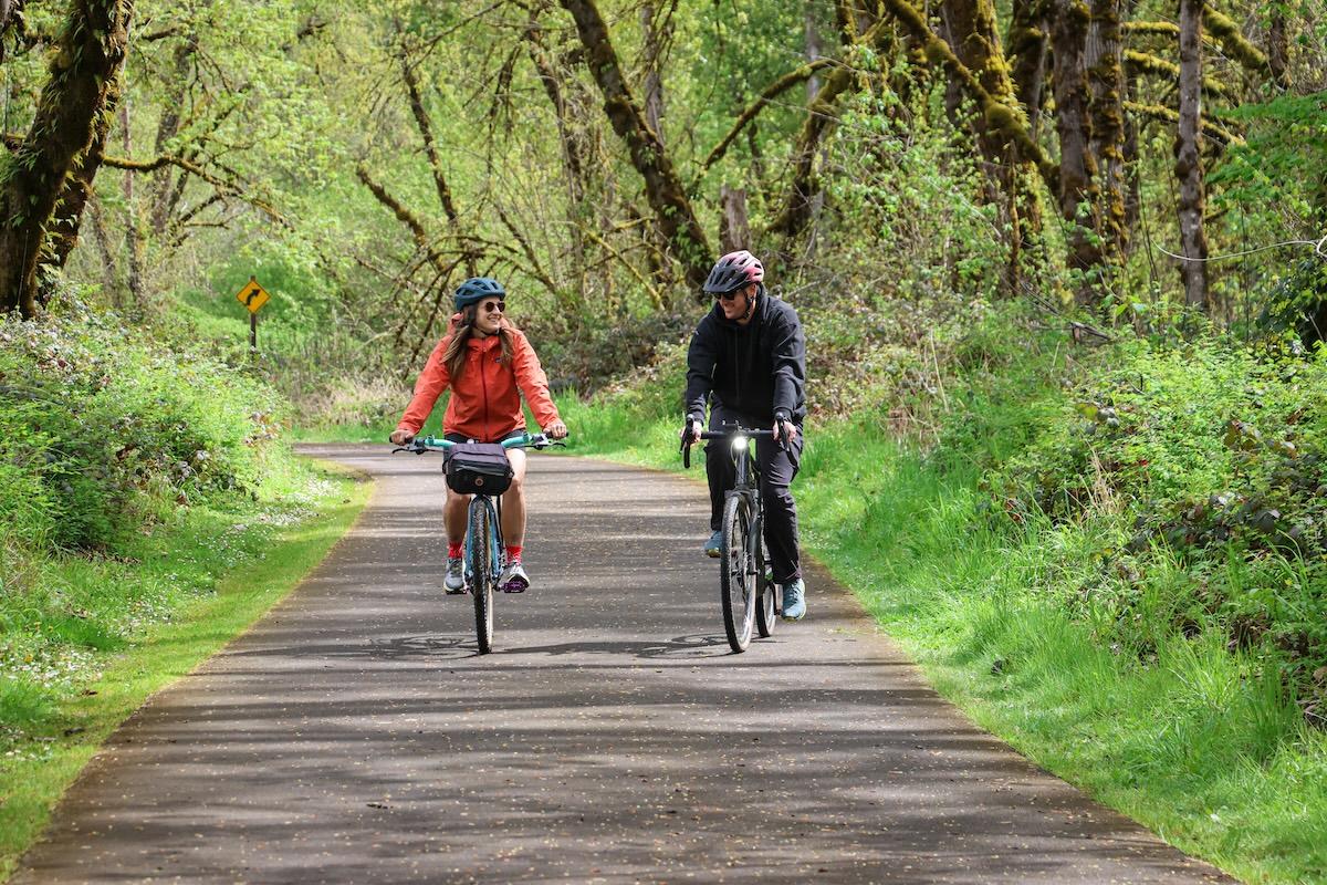 Two people riding bikes on an outdoor path.
