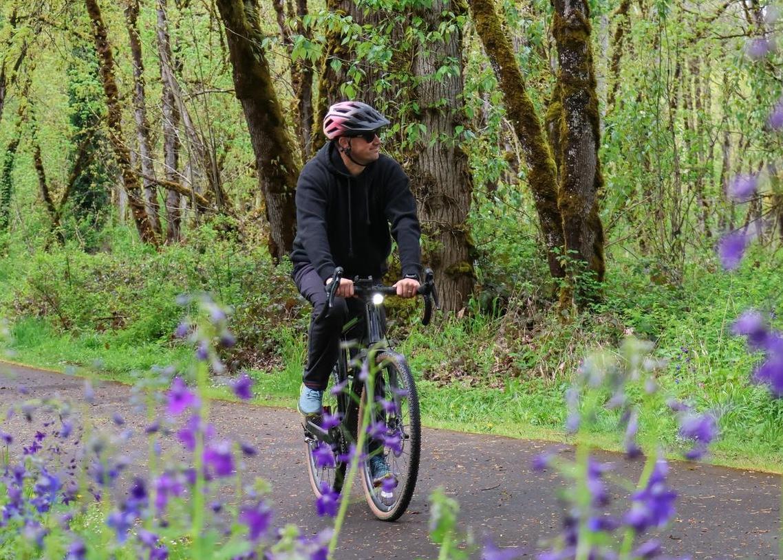 An adult rides a bike on an outdoor path.