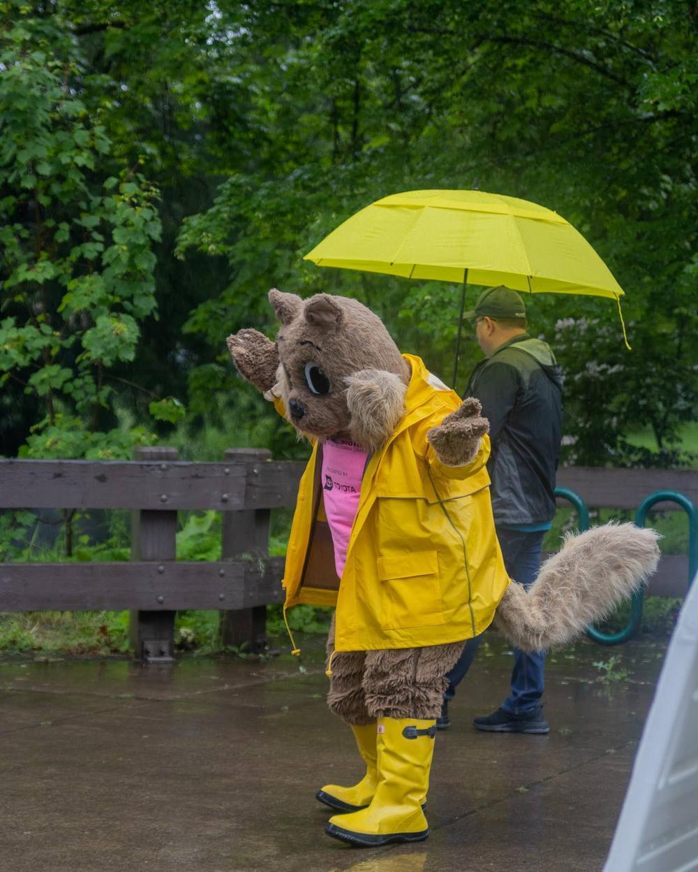 Springs the Squirrel wears a raincoat and greets attendees at Children's Celebration