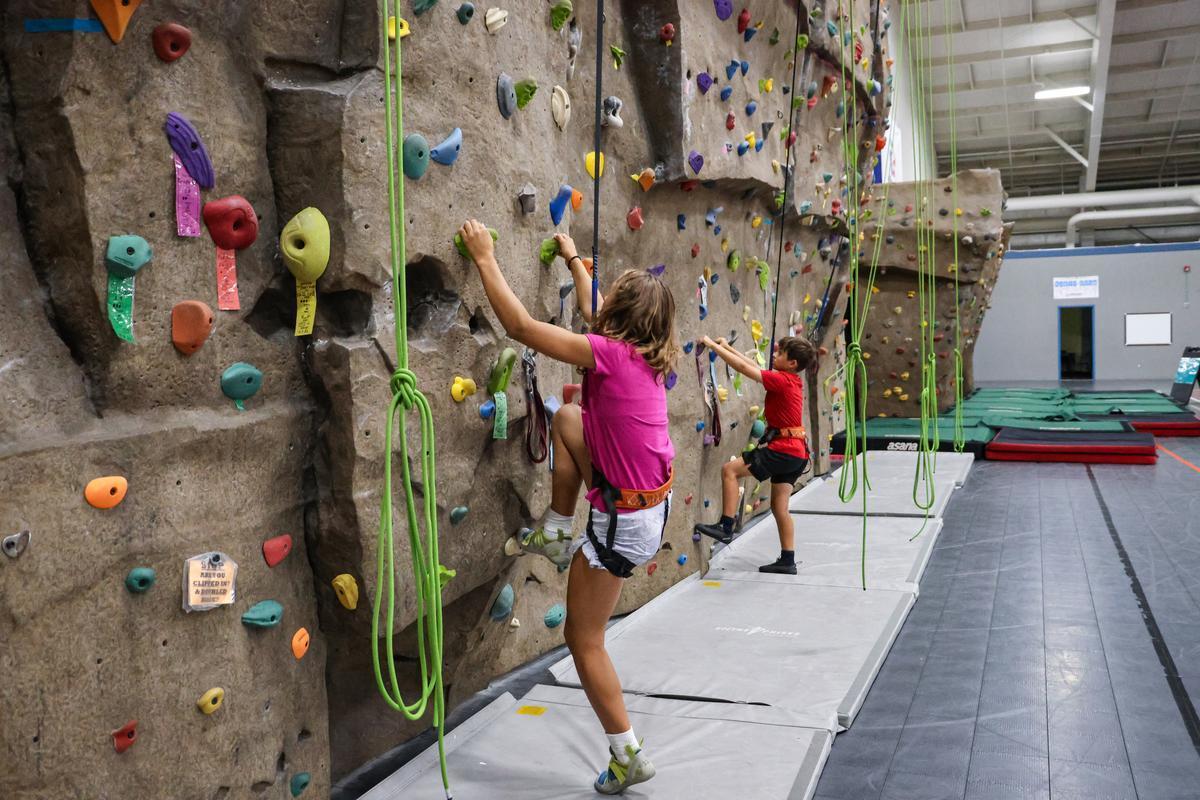 Two climbers stand at the bottom of a rock wall, about to attempt a climb.