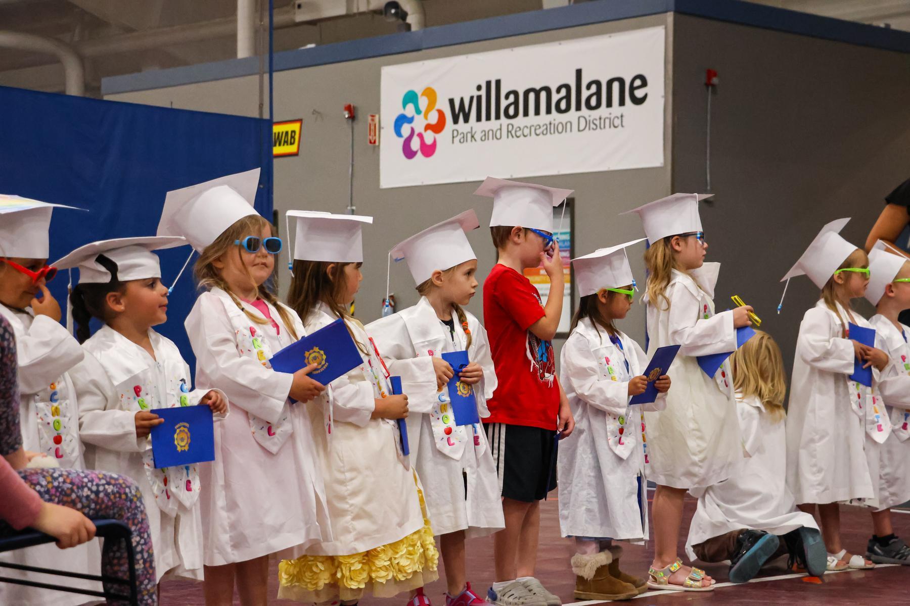 Preschoolers in graduation caps and gown wait for their graduation ceremony