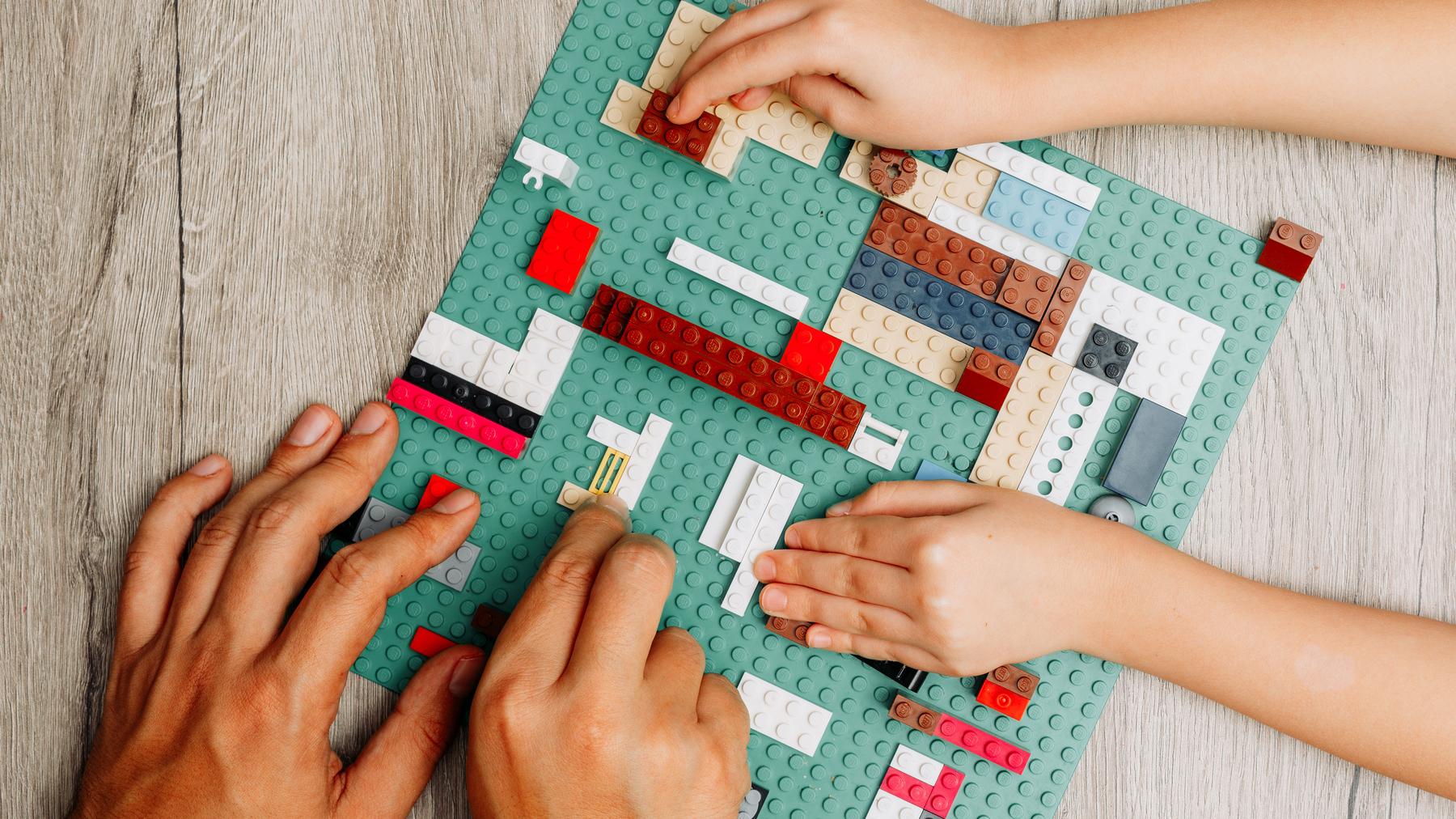 A child and adult work on a LEGO® project together