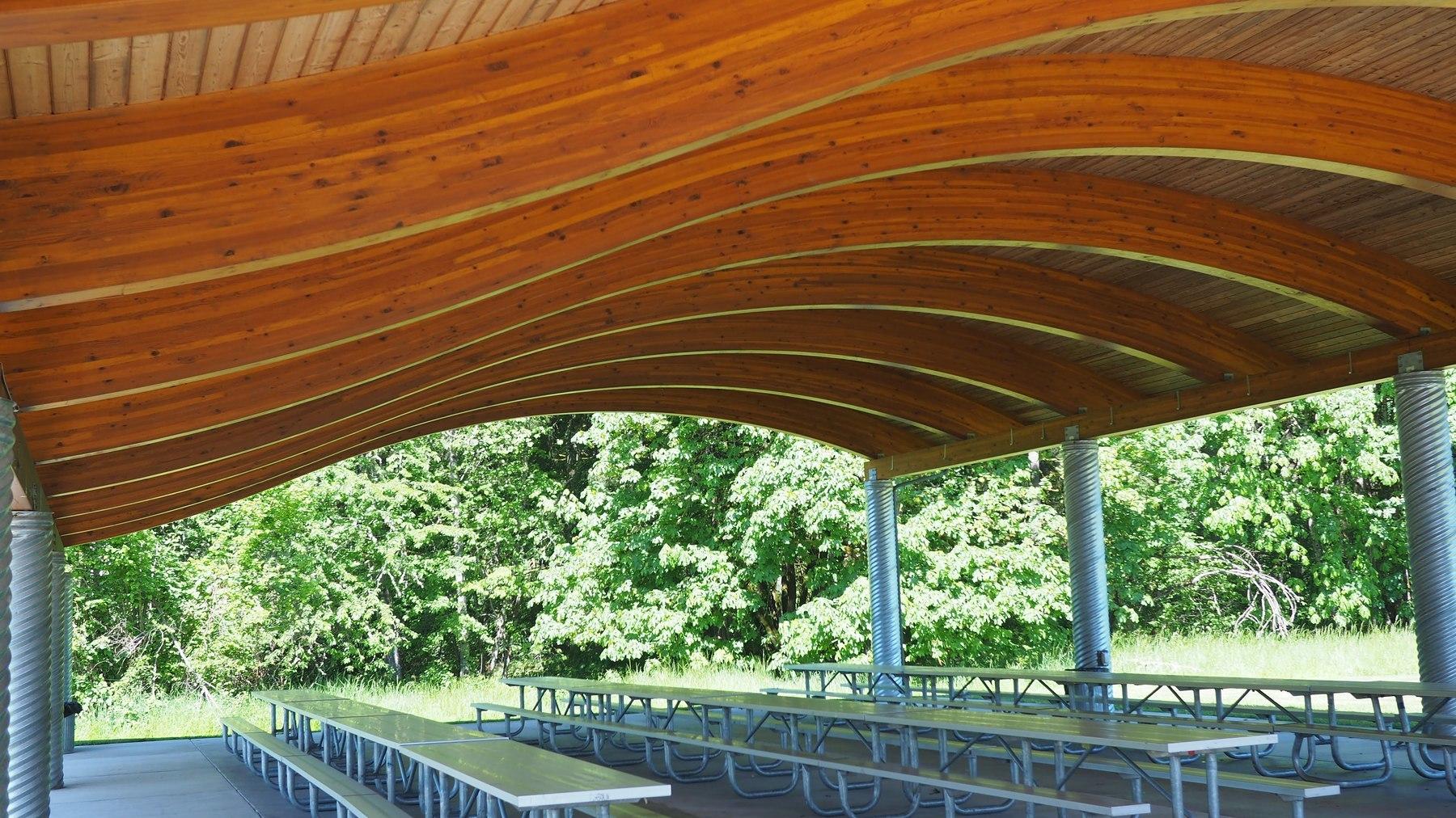 A covered picnic shelter offers three rows of picnic tables