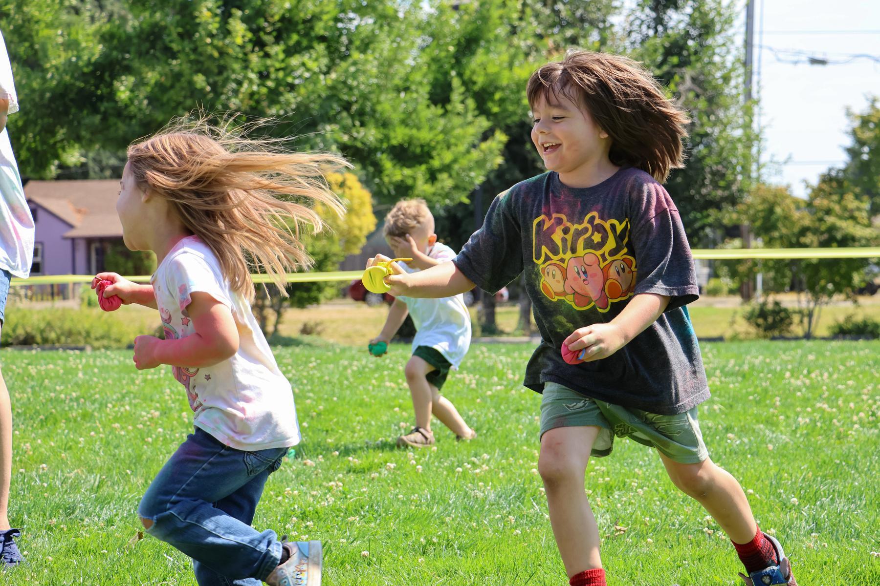 Preschoolers play outside on grassy field