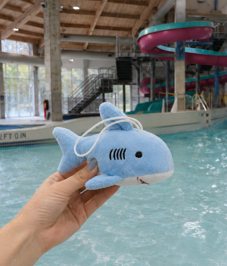A shark plush toy held in front of a pool.