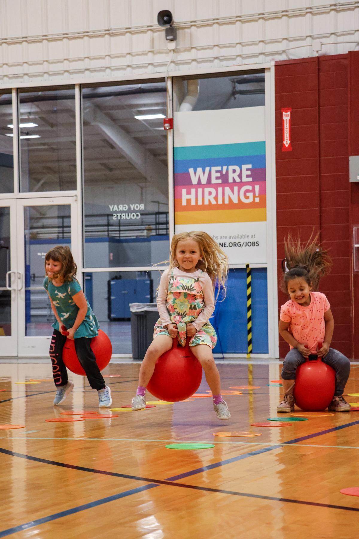 Children play on jumpy balls on indoor wood courts