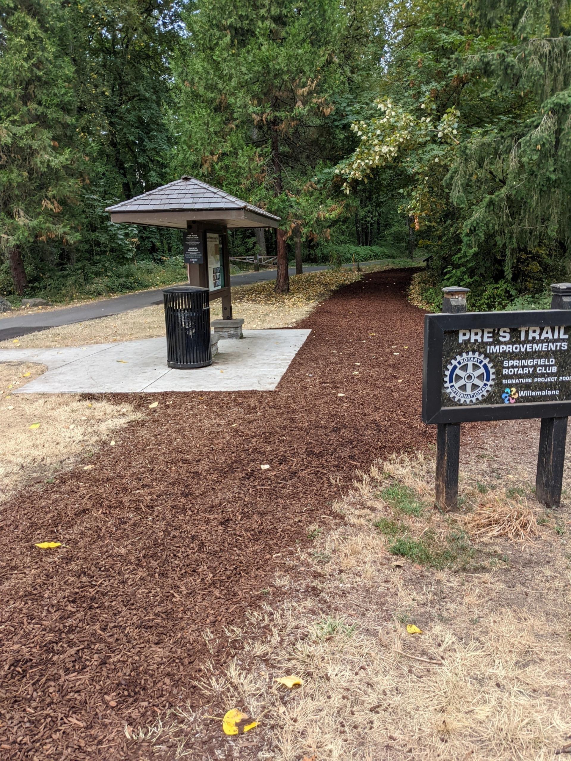 A bark/mulch running trail with a sign labeled "Pre's Trail"