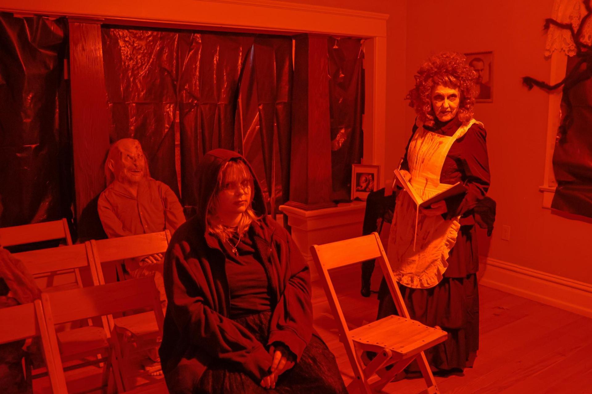 A room lit with red light and three costumed figures lingering about