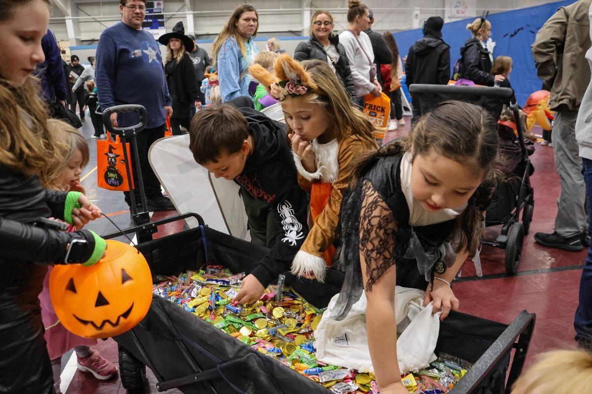 A group of children reach into a wagon filled with candy.