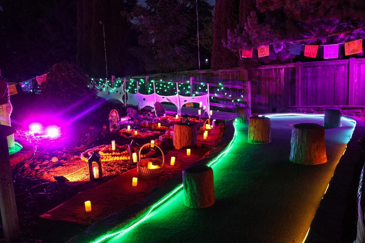 A mini golf course at night with green, pink, and orange glowing decorations.