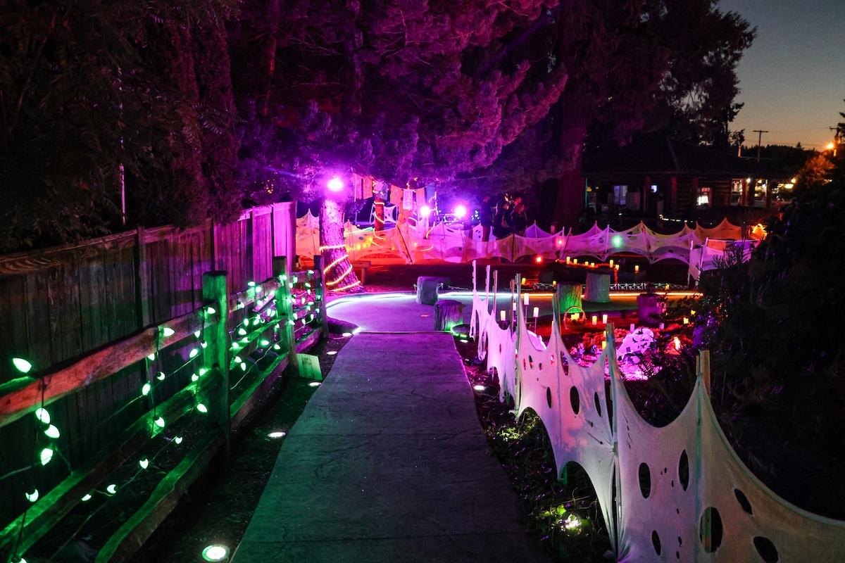 A mini golf course at night with pink and green lights and decorations.