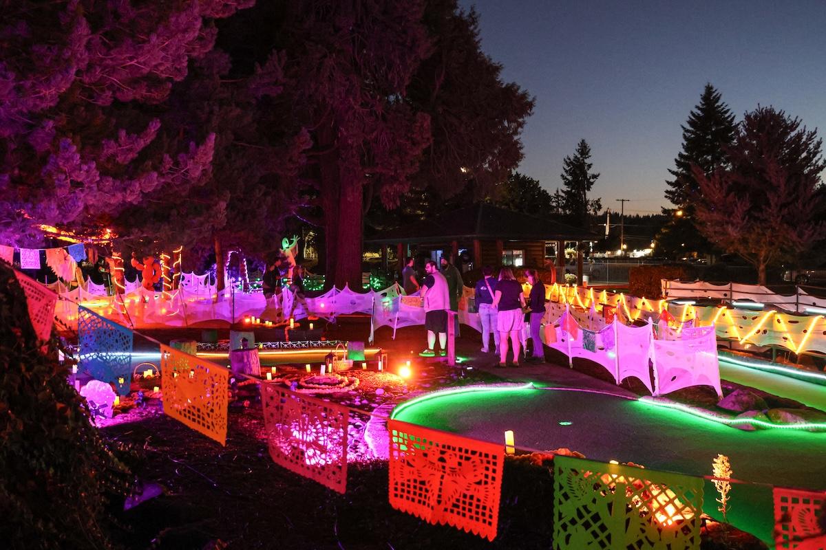 A mini golf course at night with colorful lights and decorations.