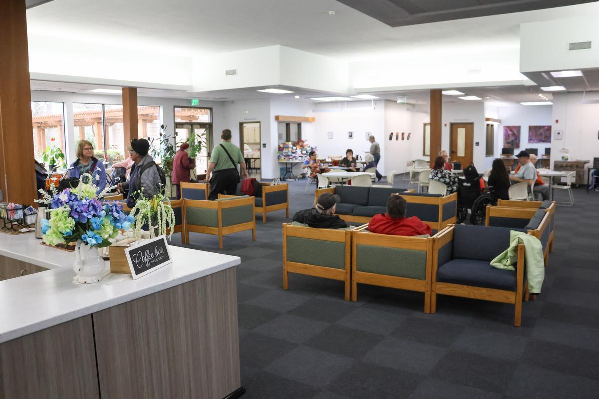 An open room with a coffee bar sign, and groups of people sitting in chairs.