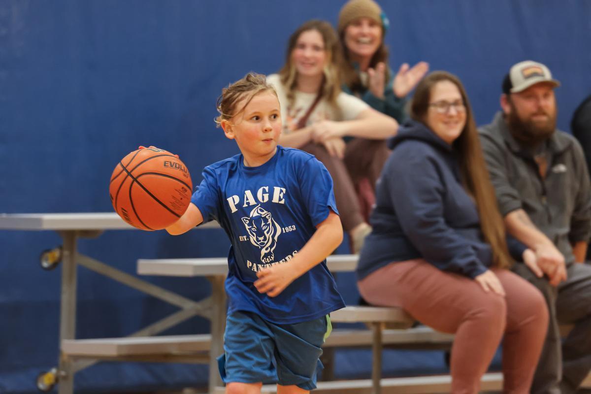 A youth basketball player dribbling in front of the bleachers
