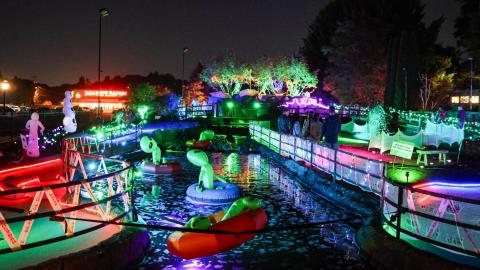 An outdoor mini golf course is covered in spooky glow-in-the-dark lights