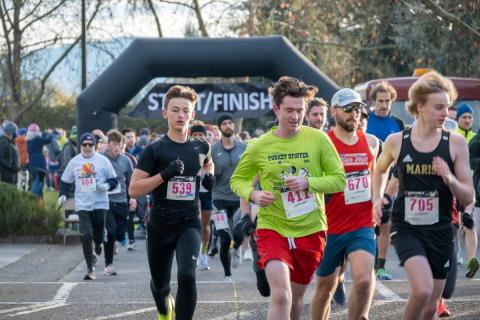 A group of runners begin running an outdoor race on pavement.